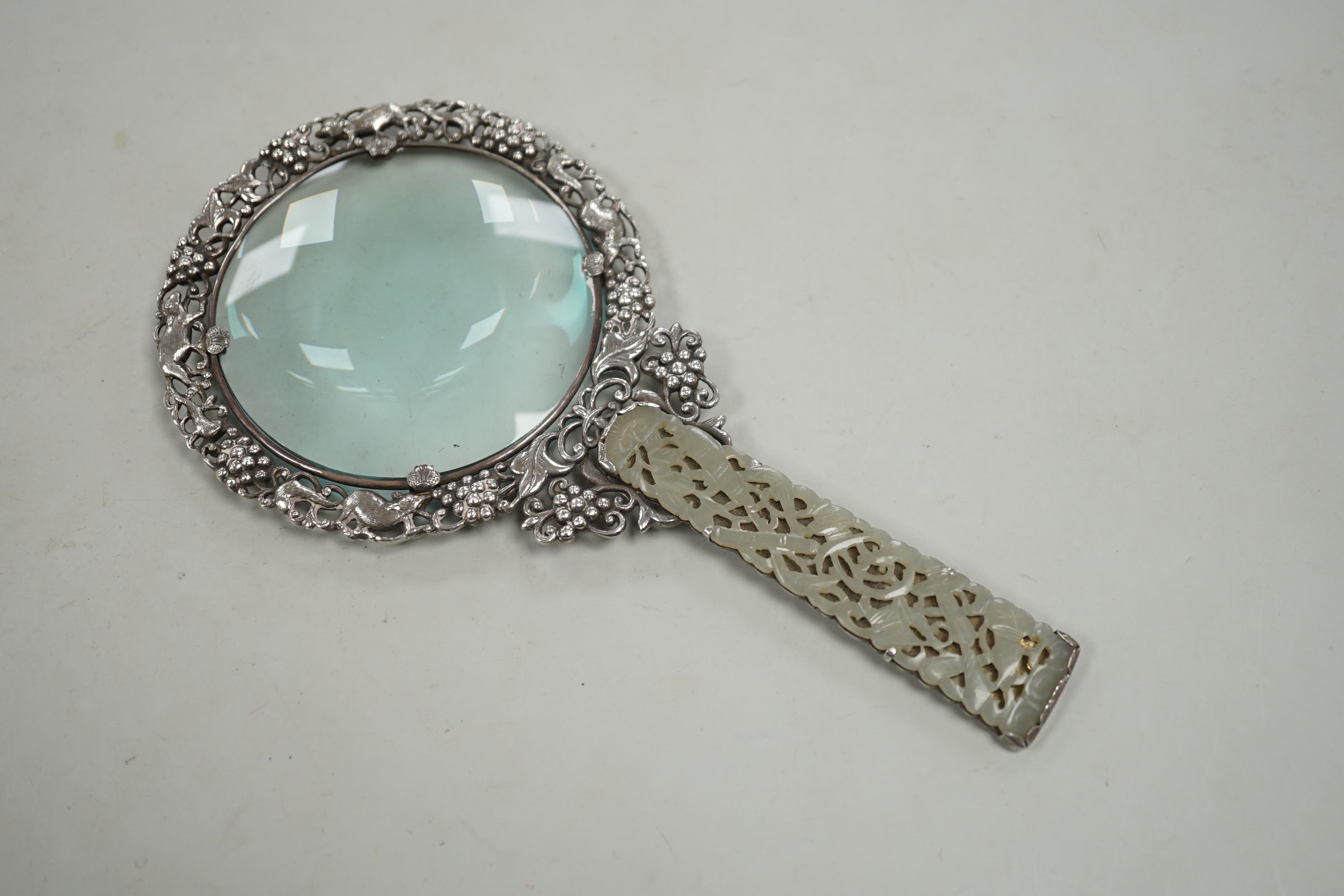 A Chinese white metal and pale celadon jade handled magnifying glass, early 20th century, stamped ‘SILVER’, 19cm long